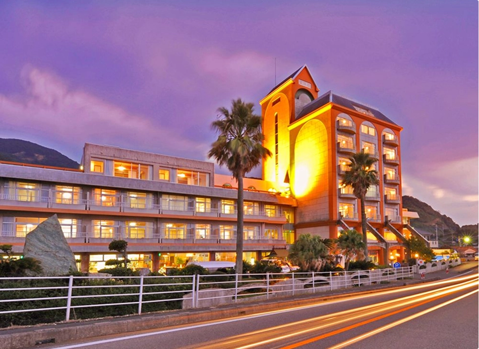 夕暮れ時の紫の空の下、ライトアップされたリゾートホテルが美しく佇んでいます。