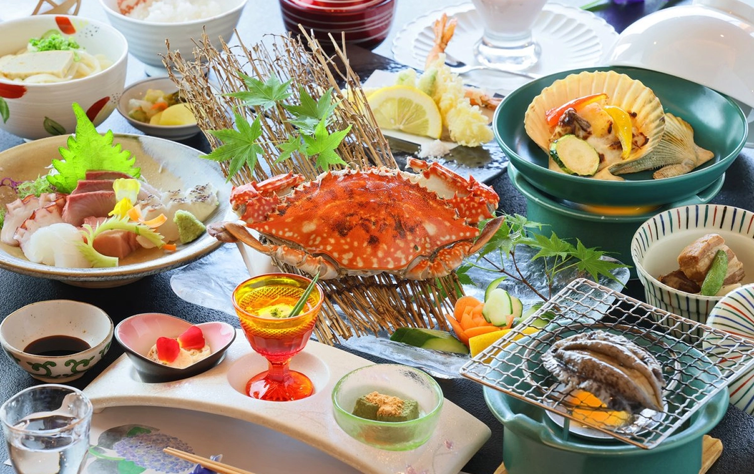 カニや刺身、アワビの網焼きなど、豪華な和食料理がテーブルいっぱいに並んでいます。
