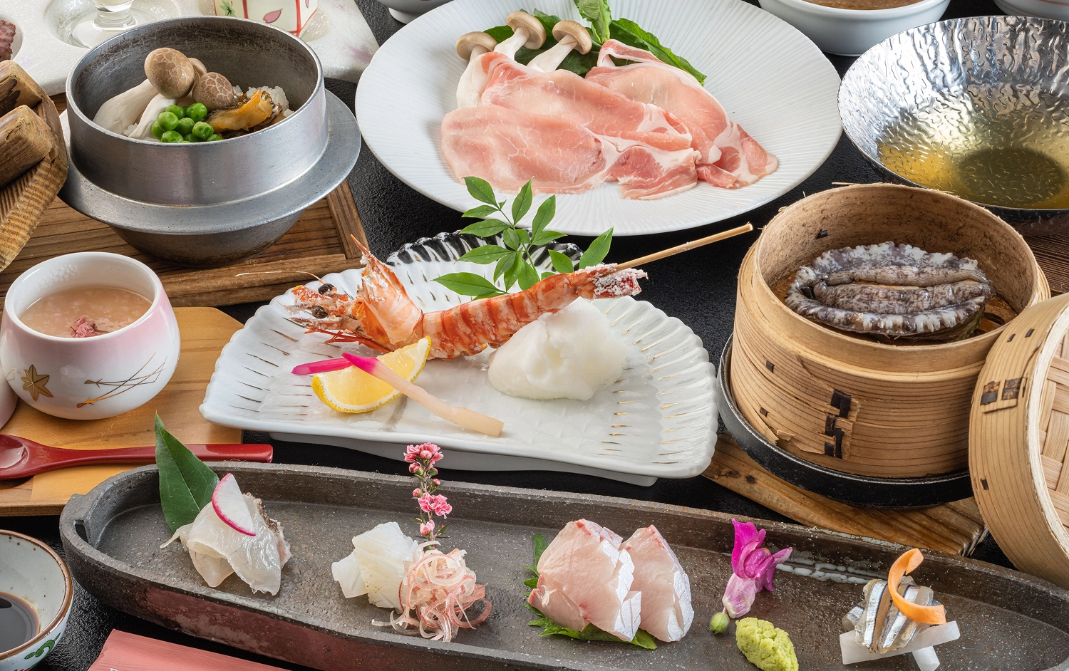 刺身や豚しゃぶ、釜飯などの豪華な和食料理がテーブルに並んでいます。