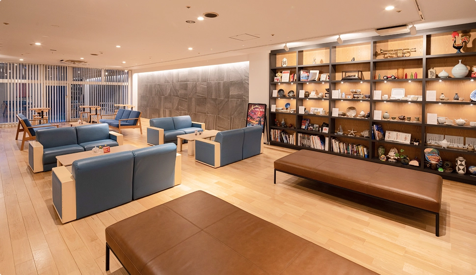 落ち着いたラウンジには青いソファが並び、大きな本棚には雑貨が飾られています。