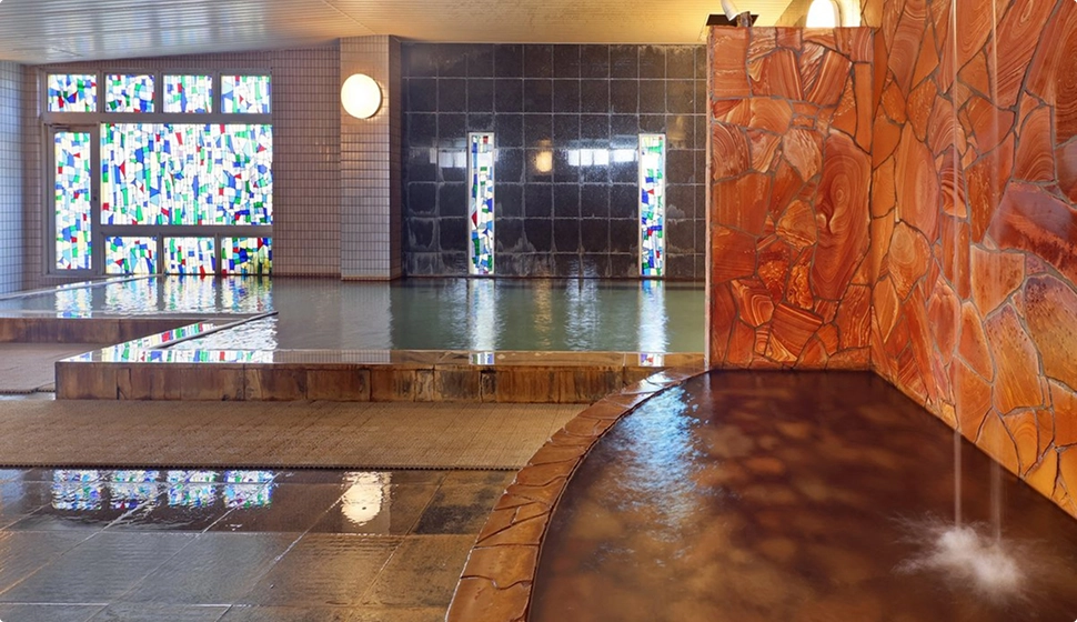 ステンドグラスが飾られた室内には、石造りの壁と湯船がある温泉施設です。