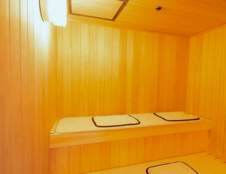 木材で囲まれたサウナ室の中に、白いマットが敷かれた段差があります。