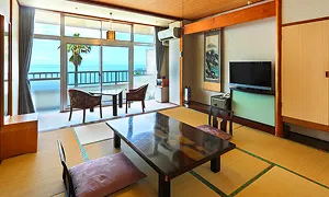 海が見える窓辺に椅子が置かれた、落ち着いた雰囲気の和室です。