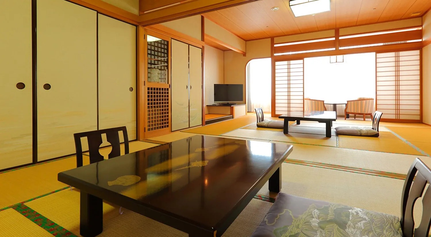 障子や畳が広がる和風の客室に、木製のテーブルと座椅子が置かれています。