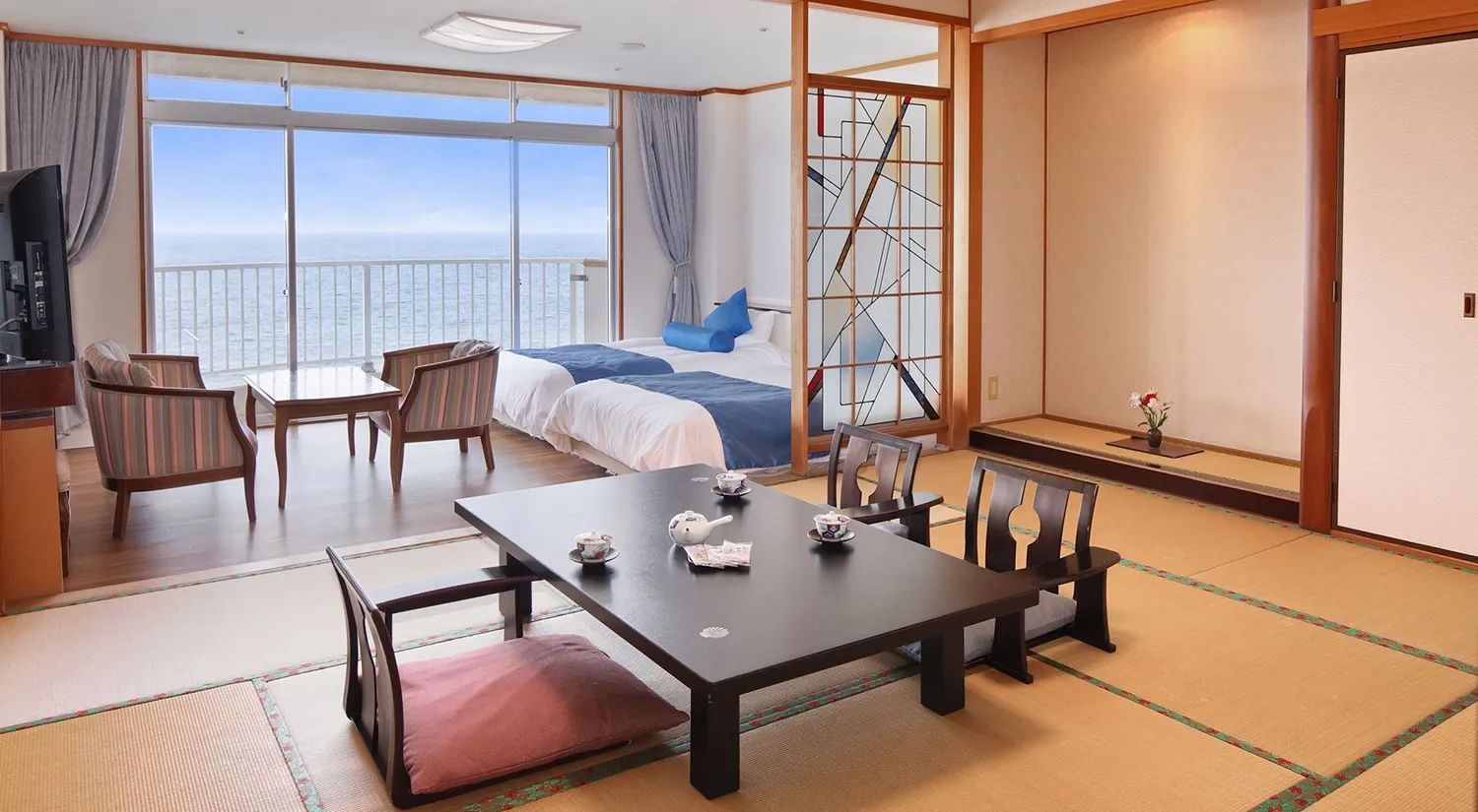 海が見える大きな窓と畳のスペースがある、和洋室の客室です。