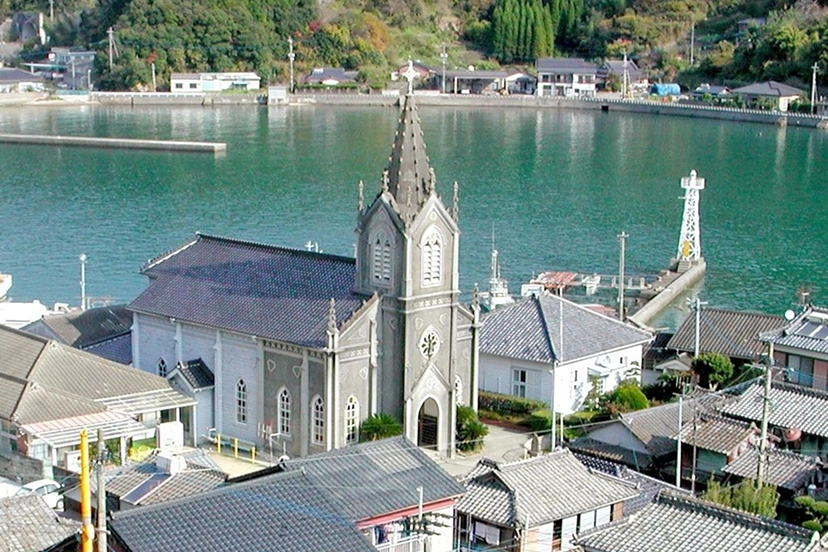 入り江に面した日本の集落に、尖塔を持つ教会が静かに建っています。